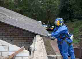 Workers removing Asbestos from roof of older house