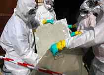 Tradesmen in protective gear removing asbestos