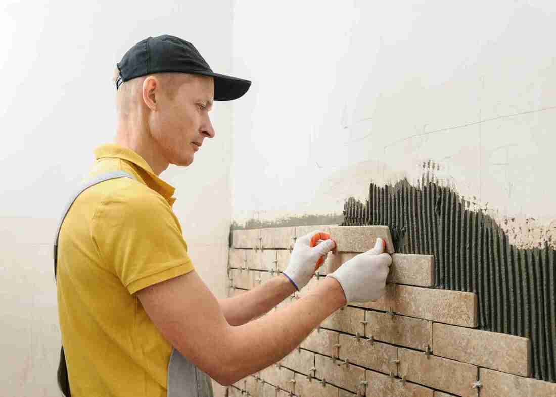 Tiler installing wall tiles